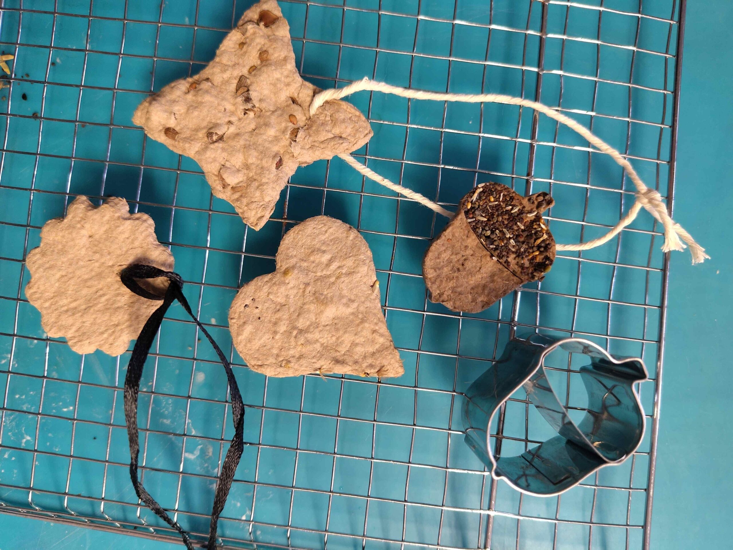 3 Papierbrei-Plätzchen für Samen-Geschenk-Anhänger liegen auf Metallgitter zum Trocknen